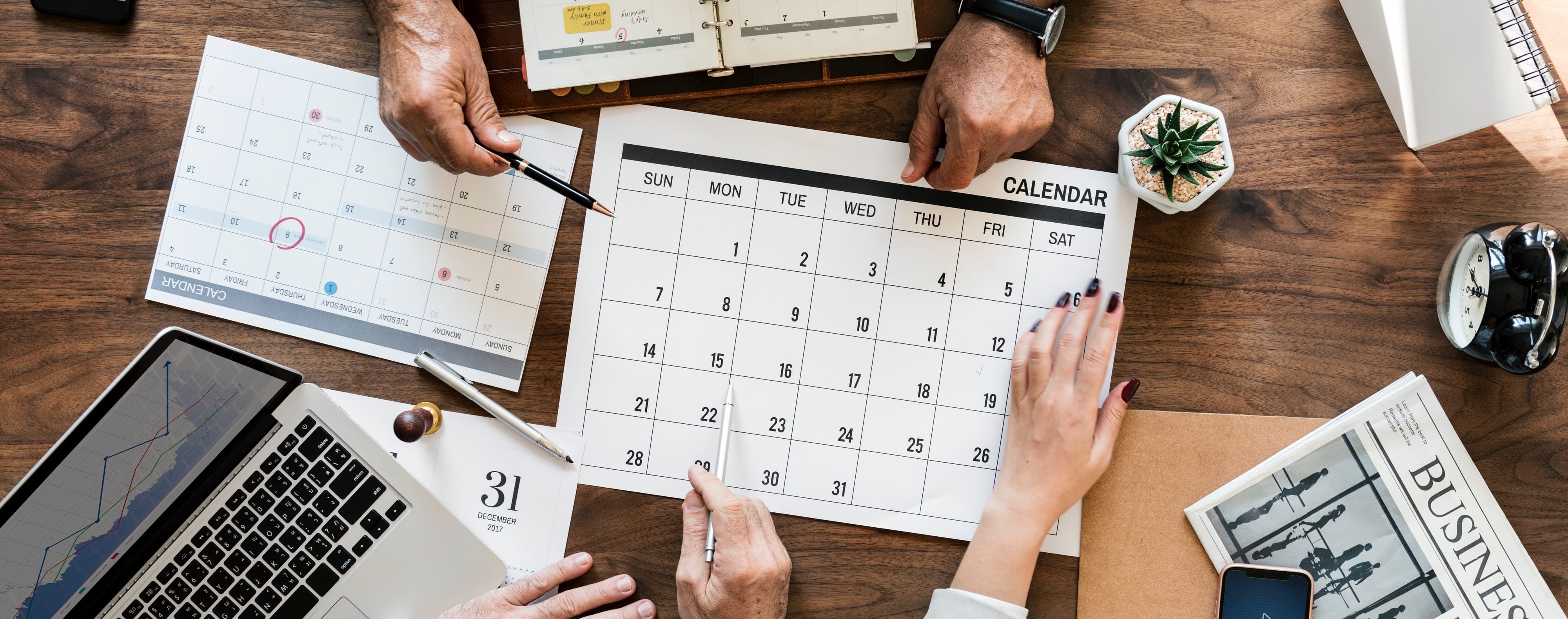 multiple business people putting marking up a calendar with their hands and pens