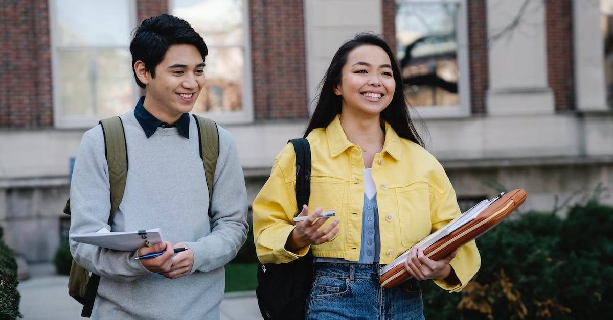 Students Walking With Binders Campus (1)