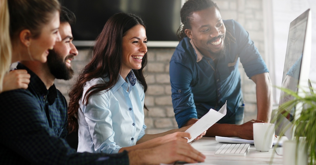 Employees Smiling Laughing Around Desk